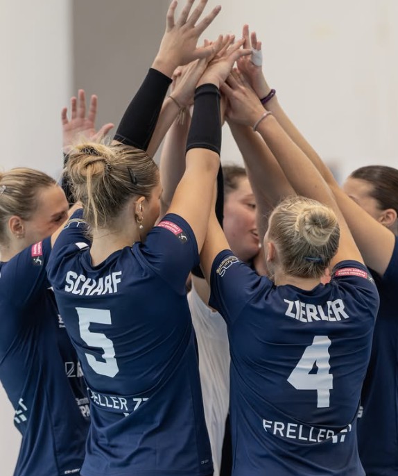 Handballspielerinnen mit verschränkten Händen in der Halle, Trikot mit Namen Scharf und Zierler